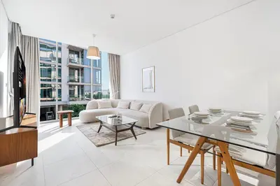 a living room with a couch and a table at Elegant 1 Bedroom Apartment with Balcony & Lagoon in District One in Dubai
