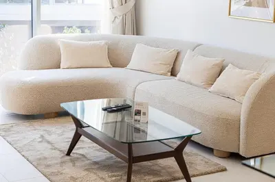 a living room with a couch and a glass coffee table at Elegant 1 Bedroom Apartment with Balcony & Lagoon in District One in Dubai