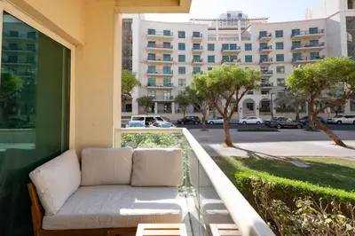 a couch on a balcony with a building in the background at Al Dhafrah 4, The Greens - Onelink in Dubai