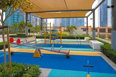 a childrens playground with a slide and swings at Vogue Downtown Burj Crown near Burj Khalifa and Dubai Mall, Three Bedroom plus Kids Room Apartment with Large Balcony and Skyline view, Access to all Amenities in Dubai