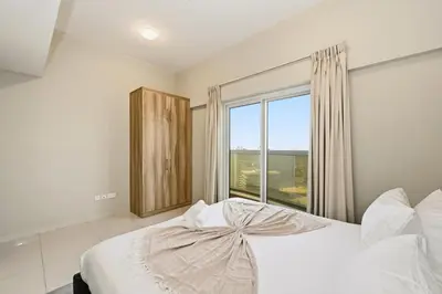 a bedroom with a bed with a large window at Modern Luxury 2BR Apartment In Dubai Sports City in Dubai