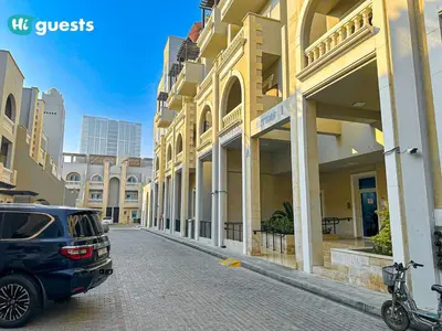 a blue car parked on a street next to a building at HiGuests - Experience Luxury 1BR Living at Autumn-1A in JVC in Dubai