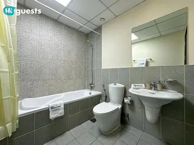 a bathroom with a toilet and a sink and a tub at HiGuests - Experience Luxury 1BR Living at Autumn-1A in JVC in Dubai