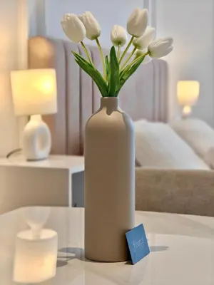 a white vase with white flowers on a table at Stylish New Studio Apartment with Balcony in Dubai