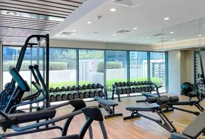 a gym with a lot of exercise equipment and windows at GuestReady - 1BR l Canal View | Business Bay in Dubai