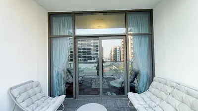 a living room with two chairs and a large window at Sleek 1BR Apt Free Pool & Gym Access in Dubai