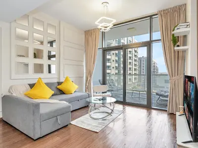 a living room with a gray couch and yellow pillows at Sleek 1BR Apt Free Pool & Gym Access in Dubai