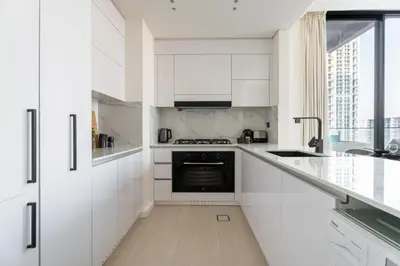 a white kitchen with white cabinets and a sink at GuestReady - Luxury with a Private Pool | 2 BHK in Dubai