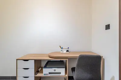 a wooden desk with a printer and two chairs at Sobha Crest Luxury Apartments in Dubai