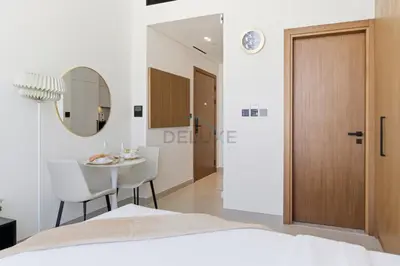 a bedroom with a bed and a table and a mirror at Modern Studio on High Floor with Stunning City Views near Circle Mall and Community Parks - Binghatti Tulip, JVC - by Deluxe Holiday Homes in Dubai