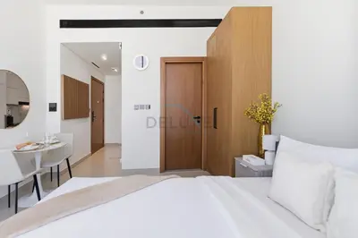 a bedroom with a white bed and a dining room at Modern Studio on High Floor with Stunning City Views near Circle Mall and Community Parks - Binghatti Tulip, JVC - by Deluxe Holiday Homes in Dubai