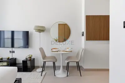 a dining room with a table and chairs and a mirror at Modern Studio on High Floor with Stunning City Views near Circle Mall and Community Parks - Binghatti Tulip, JVC - by Deluxe Holiday Homes in Dubai