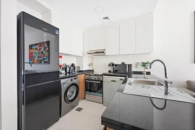 a kitchen with a sink and a refrigerator at VayK - Great 1BR Apartment in Damac Hills in Dubai