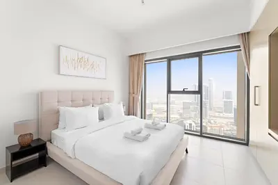 a white bedroom with a large bed and a large window at VayK - Stylish 1BR in Iconic Downtown Location in Dubai