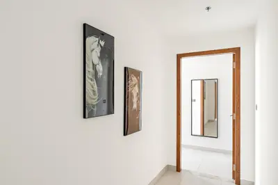 a hallway with three pictures on the wall and a mirror at Vayk - Bright and Spacious 2BR with Panoramic Marina Views in Dubai