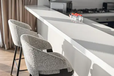 a white counter with two chairs in a kitchen at Luxury 2BR Walk-In Closet Full Burj Khalifa View in Dubai