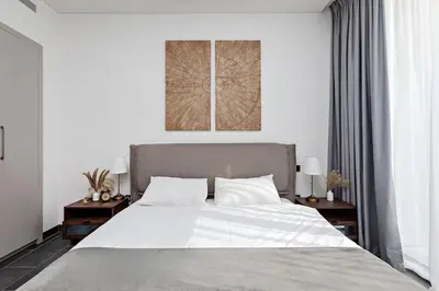 a bedroom with a large white bed with two tables at Inspiring 1BR Apartment at Sobha Hartland in Dubai
