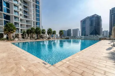 a large swimming pool with palm trees and buildings at GuestReady - Damac Prive | 1BR Canal View in Dubai