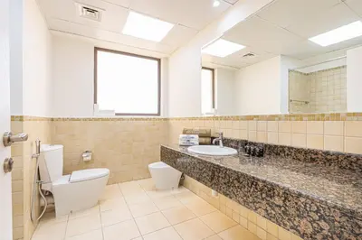 a bathroom with a toilet and a sink and a mirror at Central JBR Home Steps away from the Beach in Dubai