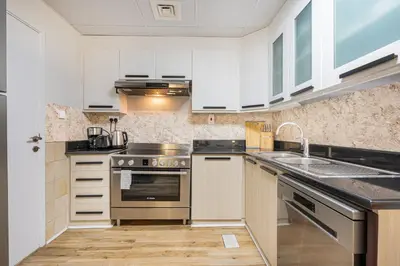 a kitchen with white cabinets and stainless steel appliances at Central JBR Home Steps away from the Beach in Dubai
