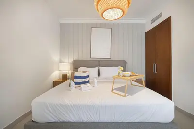 a bedroom with a large white bed with a table at Huge Modern 1BR in Creek Harbour steps to Central Park with a creek view and infinity pool by La Brisa Dubai in Dubai