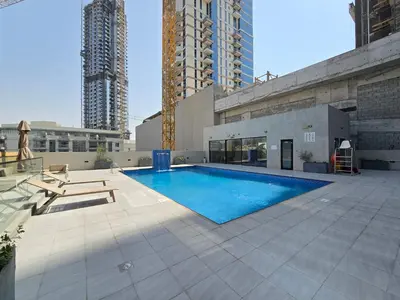 a swimming pool on top of a building with tall buildings at 1BR Poolside Serenity in JVT in Dubai