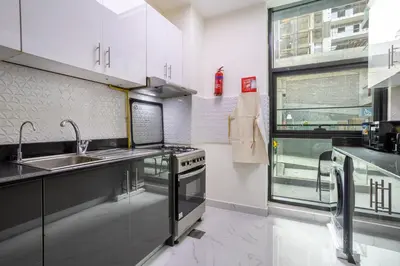 a kitchen with white cabinets and a sink and a window at 1BR Poolside Serenity in JVT in Dubai