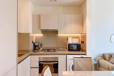 a kitchen with white cabinets and a stove top oven at 1 Bedroom Apt in Sobha Creek Vistas Tower B by Luxaura in Dubai