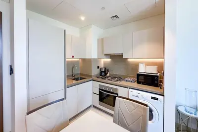 a kitchen with white cabinets and a stove top oven at 1 Bedroom Apt in Sobha Creek Vistas Tower B by Luxaura in Dubai