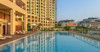 a large swimming pool with chairs and buildings at Luxury Studio on Palm Jumeirah Beach Access in Dubai