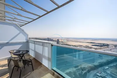 a balcony with a pool and a table and chairs at High-Floor Studio, Walking Distance to the Park and 15-Min Drive to Miracle Garden, Al Jawhara Tower, Jumeirah Village Triangle by Deluxe Holiday Homes in Dubai