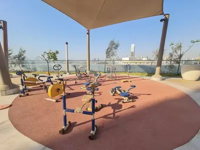 a gym with rows of exercise equipment on a red carpet at High-Floor Studio, Walking Distance to the Park and 15-Min Drive to Miracle Garden, Al Jawhara Tower, Jumeirah Village Triangle by Deluxe Holiday Homes in Dubai