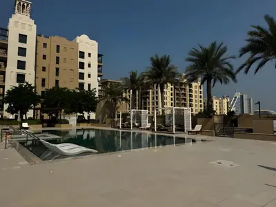 a large swimming pool with palm trees and buildings at Luxury 1BR in Madinat Jumeirah Living in Dubai