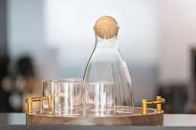 a glass bottle and two glasses on a table at Elegant 1-Bedroom Apartment at Downtown Dubai with Stunning Canal & Skyline Views in Dubai