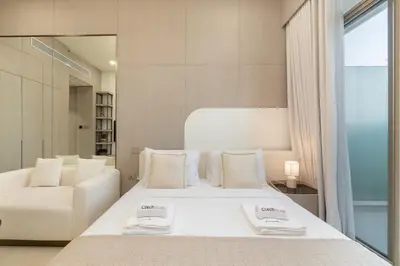 a bedroom with a large white bed and a chair at Elegant Studio Escape in JVC - by Czechin in Dubai