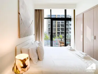 a bedroom with a large white bed with a large window at Bright City ST with Balcony l Pool, Gym & Wi-Fi in Dubai