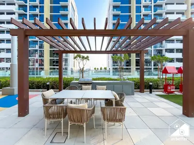 a patio with a table and chairs under a wooden pergola at Bright City ST with Balcony l Pool, Gym & Wi-Fi in Dubai