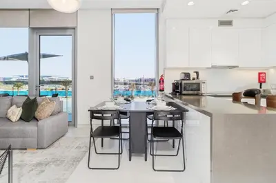 a kitchen and living room with a table and a couch at Lagoon-Facing 1BR, Minutes from Downtown and Business Bay, Near Dubai Water Canal - District One Phase III Residences 18 by Deluxe Holiday Homes in Dubai