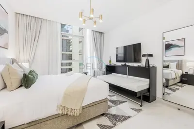 a white bedroom with a large bed and a desk at Lagoon-Facing 1BR, Minutes from Downtown and Business Bay, Near Dubai Water Canal - District One Phase III Residences 18 by Deluxe Holiday Homes in Dubai