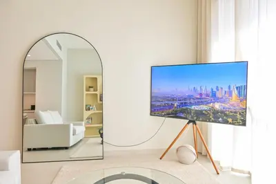 a living room with a flat screen tv on a stand next to a mirror at Vida Residences - Luxury & Serenity - Creek Beach in Dubai