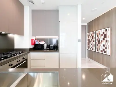 a kitchen with white cabinets and a stove top oven at Luxury Canal-View Retreat l 3BR with Balcony & Pool in Dubai
