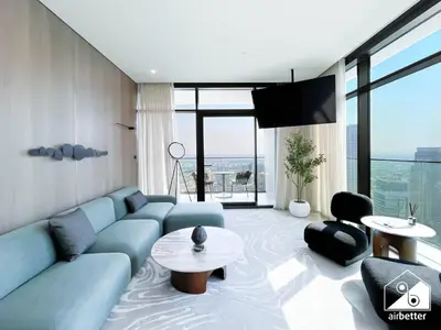 a living room with a blue couch and a tv at Luxury Canal-View Retreat l 3BR with Balcony & Pool in Dubai