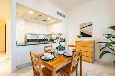 a kitchen and dining room with a wooden table and chairs at Best Business Bay Location - Direct Views of Canal and Al Khail Racecourse - 1 min from Al Habtoor Palace in Dubai