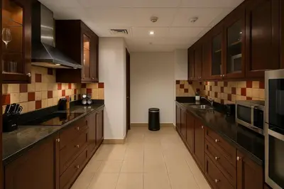 a large kitchen with wooden cabinets and appliances at Downtown Burj Khalifa View One Bedroom Apartment in Dubai