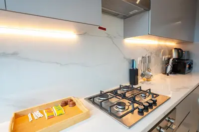 a kitchen with a stove and a wooden cutting board at EasyGo - Chic 2-Bedroom with Dubai Skyline View in Dubai