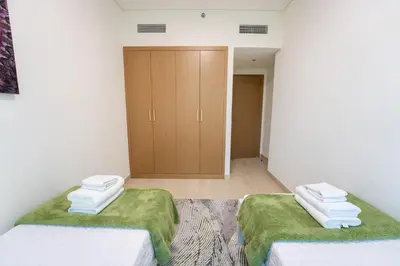 two beds in a room with green sheets and towels at EasyGo - Chic 2-Bedroom with Dubai Skyline View in Dubai
