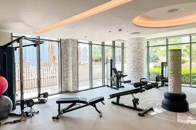 a gym with several treadmills and machines in a room with windows at Bright 1BR Walk to Beach Marina Vista Dubai in Dubai