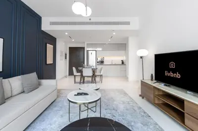 a living room with a couch and a tv at Bright 1BR Walk to Beach Marina Vista Dubai in Dubai