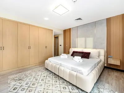 a large white bed in a room with wooden cabinets at New Renovate Huge Flat w Canal & Burj Khalifa view in Dubai