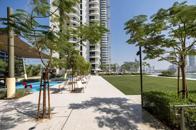 a park with a pool and trees and a building at Palace Beach Residences By Luxe Living - Palm & Marina View in Dubai